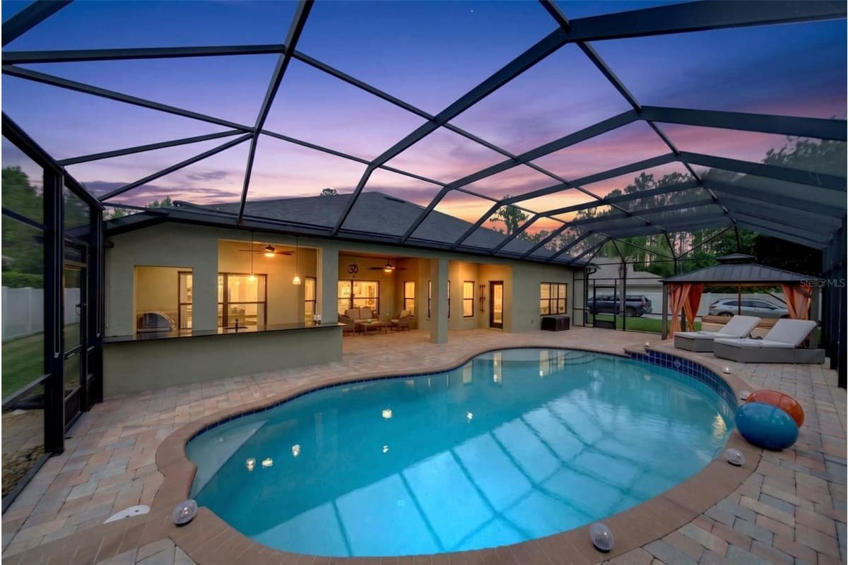Screened saltwater pool at twilight, 91 Ethan Allen Drive, Palm Coast, a home sold by Marilynn Wolfe